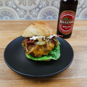 Irish Cheddar Burger mit WonderGreen Schmorzwiebeln auf schwarzem Teller